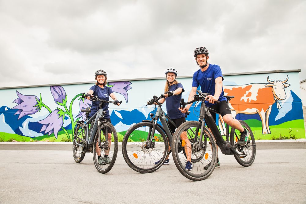 3 E-Mountainbiker vor einer Graffiti-Wand